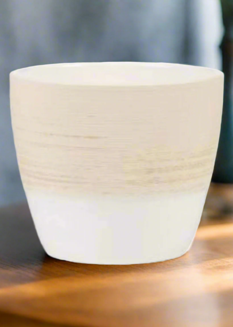 White ceramic pot on a wooden surface with a blurred background