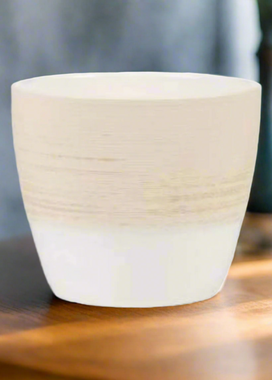 White ceramic pot on a wooden surface with a blurred background